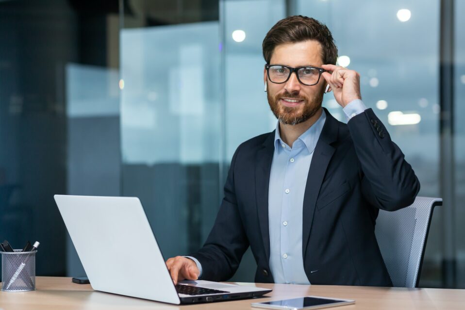 A young businessman, lawyer, legal defender, sits in the office at the table, works at the laptop