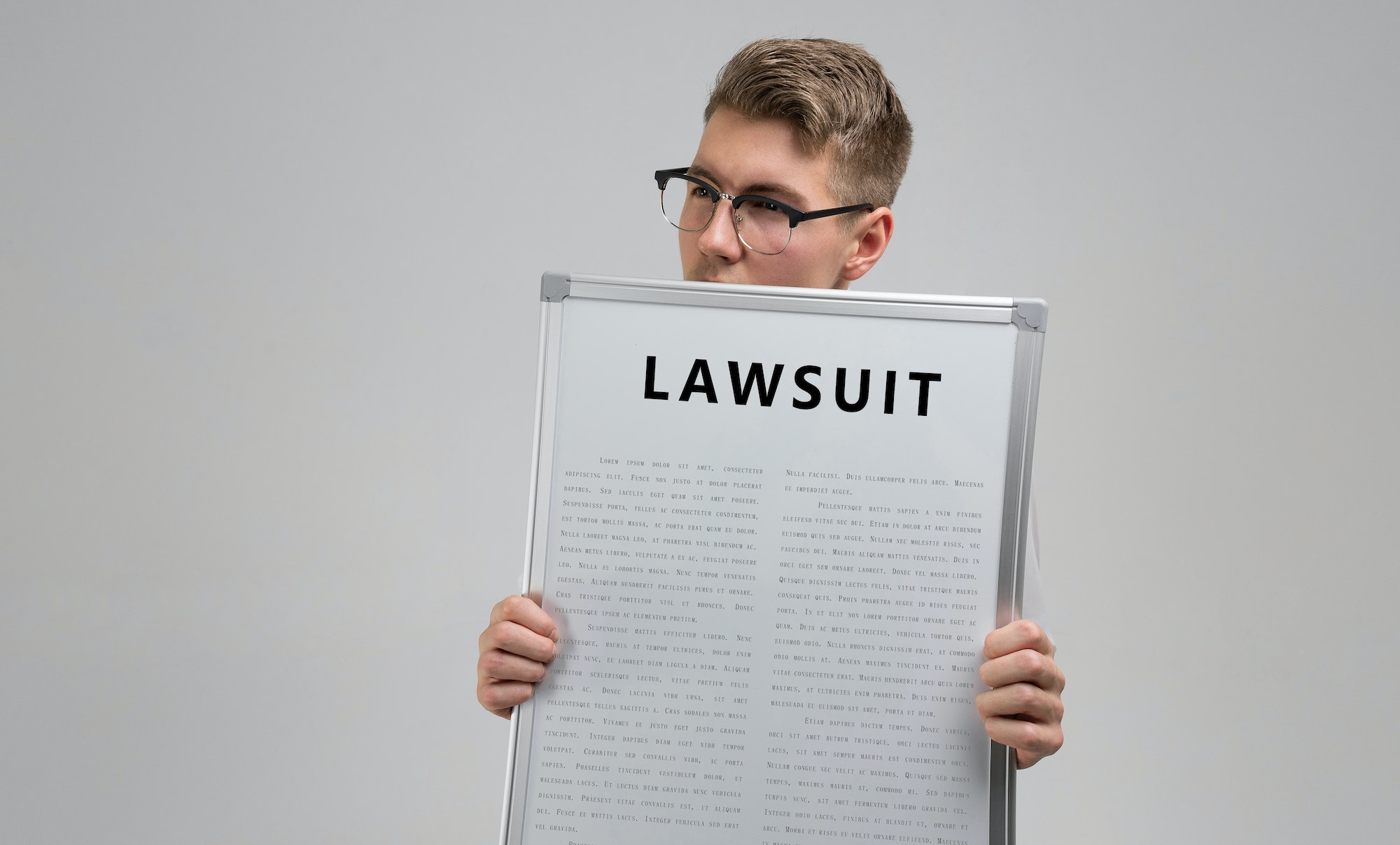 young man keeps in front of him a poster with the inscription lawsuit isolated on a light background